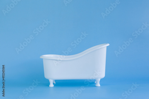 Empty white bathtub toy on a blue background and soap bubbles foam