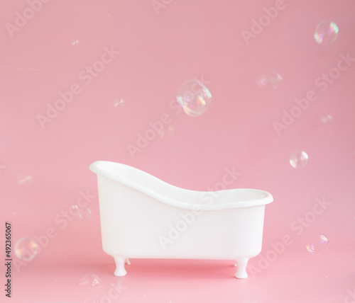 Empty white bathtub toy on a pink background and soap bubbles foam