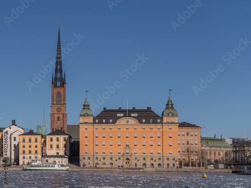 Houses and church in the island Riddarholmen at the bay Riddarfjärden with ice floes a sunny winter day in Stockholm