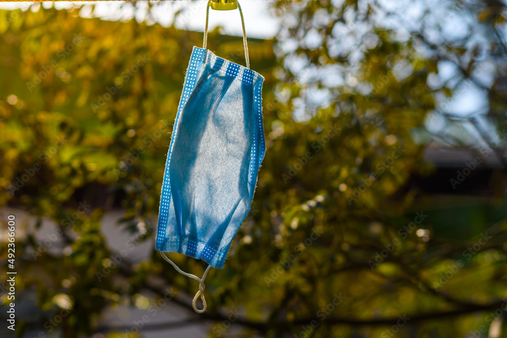 Close up of surgical mask hanging on laundry string with natural background