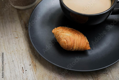 Traditional Malay food is known as Karipap or Curry Puff on the dark plate with a cup of coffee photo