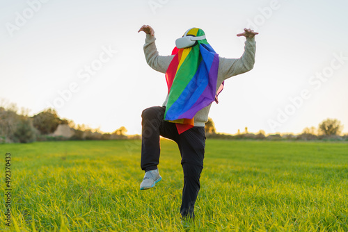A person with a rainbow flag exploring virtual reality in a green meadow and doing kung fu