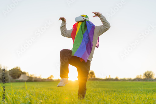 Person with the lgbt flag and virtual reality glasses doing kung fu in a meadow at sunset