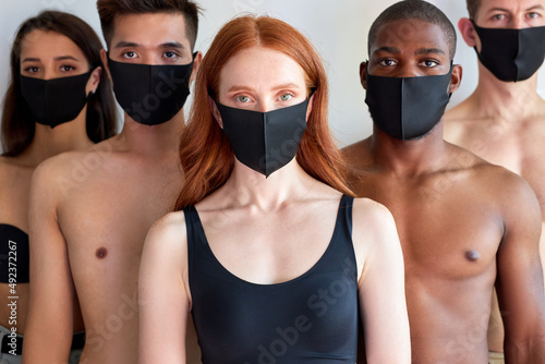 young people with protective mask stand looking at you isolated on white background, concept of protection from flu A-H1N1 coronavirus omicron. portrait of diverse people. redhead female in center