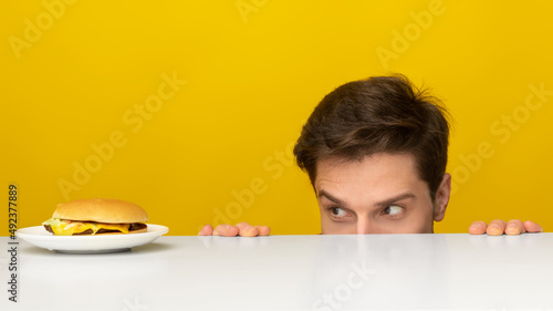 Hungry Guy Looking At Burger Peeping Out Table