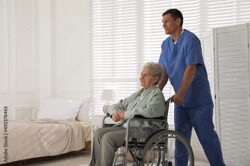 Caregiver assisting senior woman in wheelchair indoors. Home health care service Caregiver assisting senior woman in wheelchair indoors. Home health care service