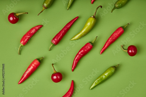 Flat lay composition with many hot chili peppers on green background. fresh fruits vegetables concept. top view