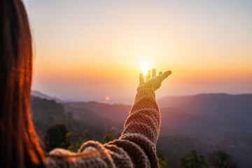Young woman hand reaching for the mountains during sunset and beautiful landscape