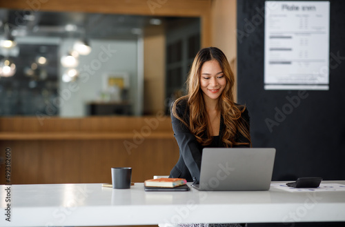 Foto Charming Asian businesswoman sitting in the office with a digital laptop computer