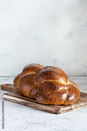Challah or Hala is a traditional jewish sweet fresh sabbath Braided bread (loaf), fresh bun on cutting board. Brioche on breakfast table. 