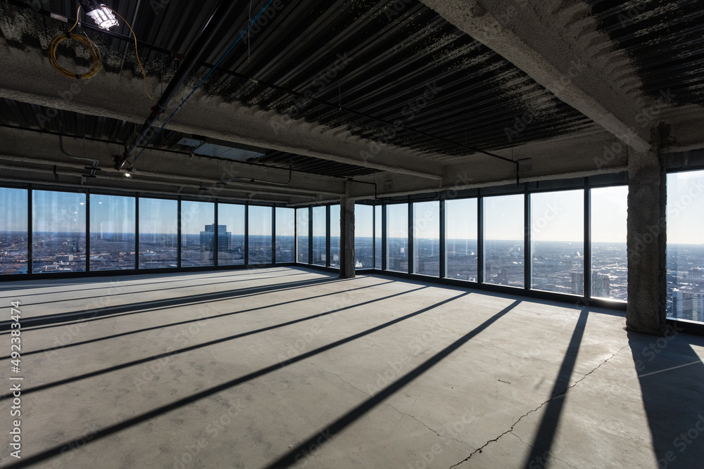 Dramatic shadows along the floor of empty office space awaiting development in a tall highrise in a large urban area Dramatic shadows along the floor of empty office space awaiting development in a tall highrise in a large urban area