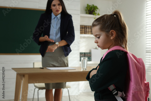 Fényképezés Teacher pointing on wrist watch while scolding pupil for being late in classroom