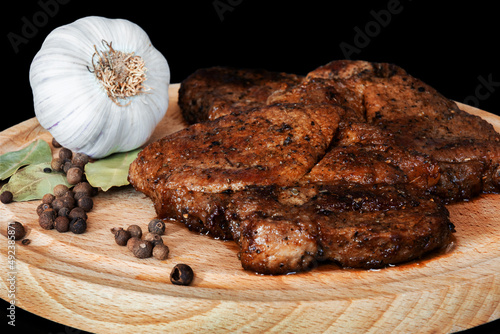 mięso smażone z przyprawami na desce z czosnkiem na czarnym tle