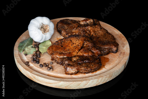 mięso z grilla z czosnkiem i pieprzem na desce na czarnym tle
