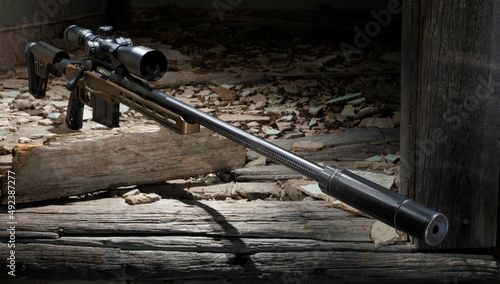 Bolt action rifle and silencer in old building photo