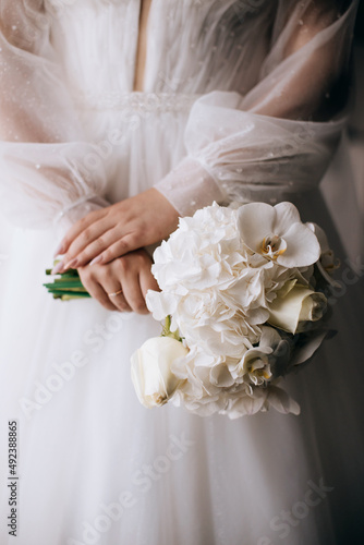 The bride holds an elegant bouquet of white orchids. Wedding morning