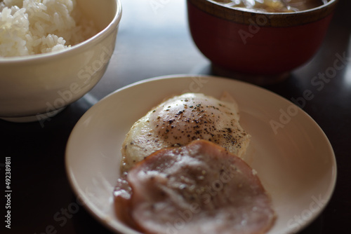 大量の黒胡椒がかかっているハムエッグと、ご飯、味噌汁の食事