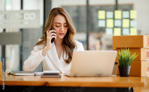 Startup SME small business entrepreneur SME or freelance Asian woman using a laptop with box, Young success Asian woman with her hand lift up, online marketing packaging box and delivery, SME concept.