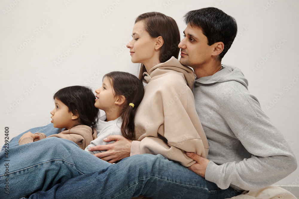Portrait of happy caucasian parents posing with their little daughters at home, beige pastel background Portrait of happy caucasian parents posing with their little daughters at home, beige pastel background