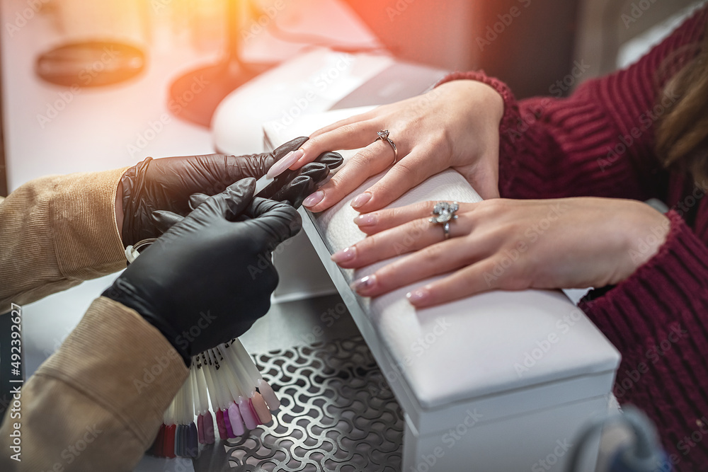 Manicure master with client in beauty salon chooses color of gel polish Manicure master with client in beauty salon chooses color of gel polish