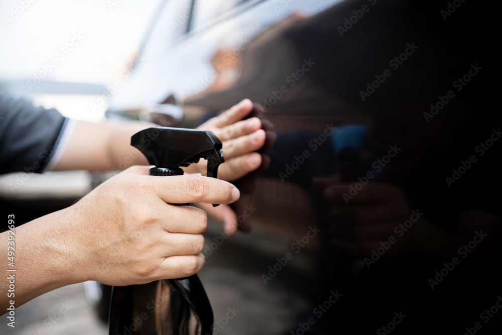 Car clean concept, Close up Hand a man holding clean spray wax and check the surface of the car paint to take care of the surface of the car from washing Car clean concept, Close up Hand a man holding clean spray wax and check the surface of the car paint to take care of the surface of the car from washing