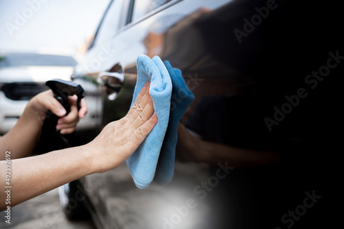 Car clean concept, Hand a man holding microfiber cloth and clean spray wax to take care of the surface of the car from washing