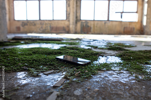 mobile phone on the floor of an abandoned enterprise overgrown with moss and ice