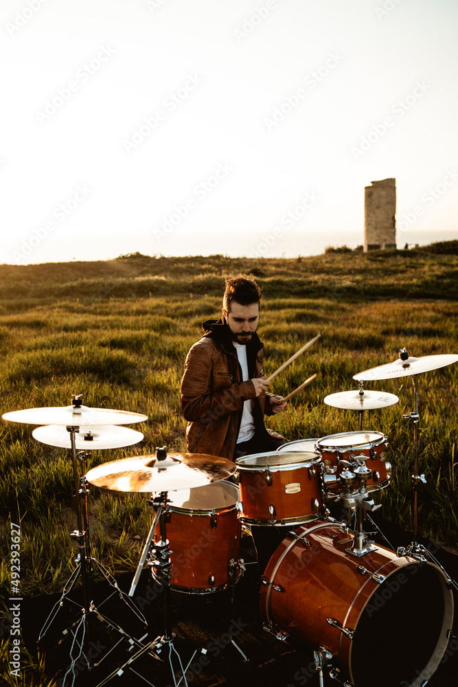 A south spain drummer man playing in a field at sunset very hard