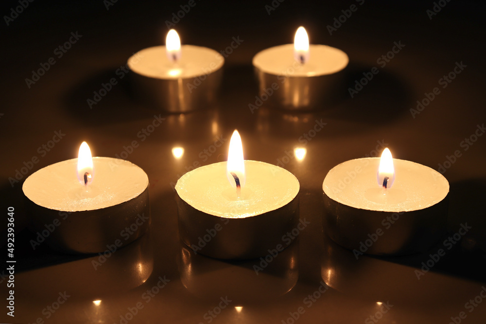 pointLots of candles on a wooden in the darkness tablefocusspot specifically in on a dark color background. pointLots of candles on a wooden in the darkness tablefocusspot specifically in on a dark color background.