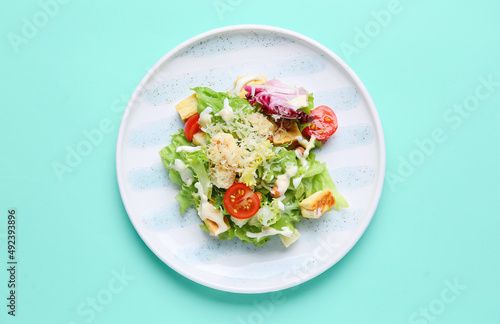 Plate with tasty vegan Caesar salad on turquoise background