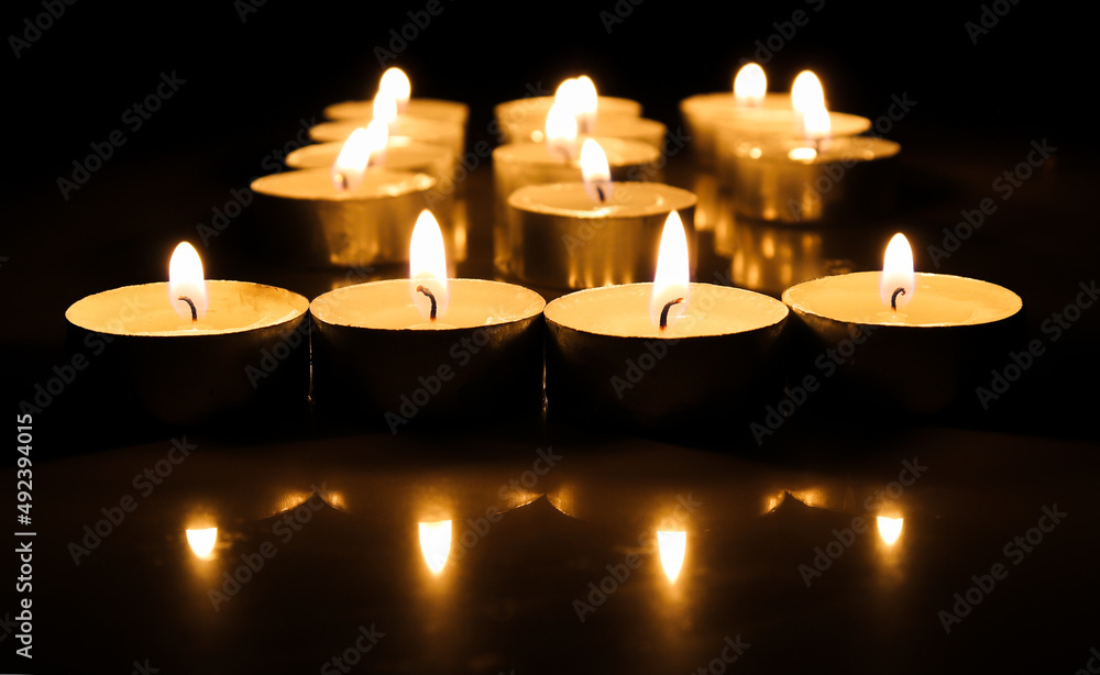 pointLots of candles on a wooden in the darkness tablefocusspot specifically in on a dark color background.