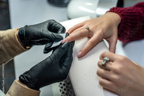 Female client receiving a manicure by nail beautician in salon.