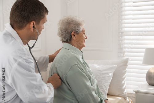 Caregiver examining senior woman in room. Home health care service