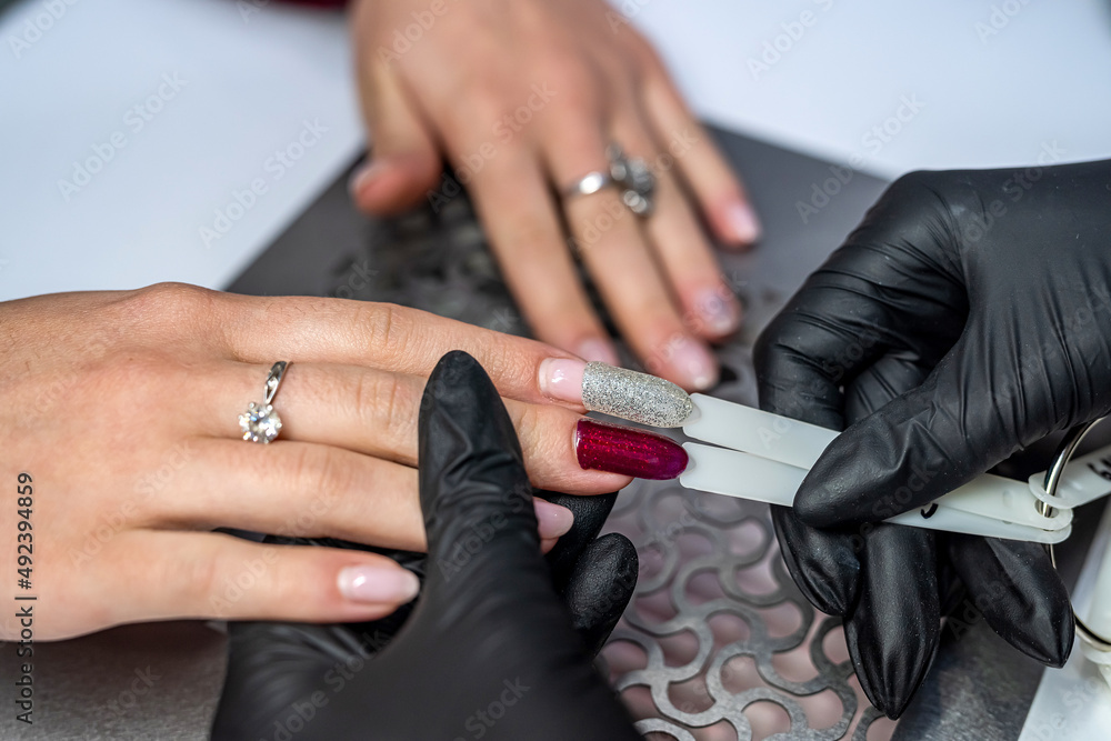 Master with a customer choosing color of nail polish in beauty salon