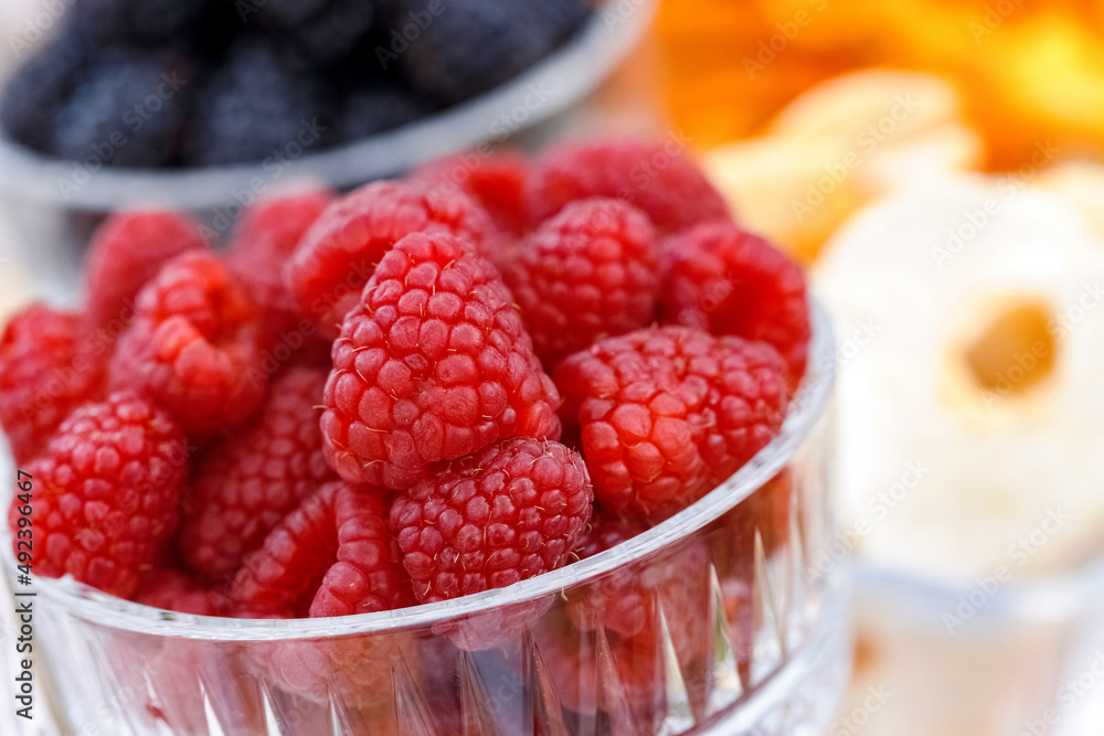 Glass with fresh red raspberries closeup on table Glass with fresh red raspberries closeup on table