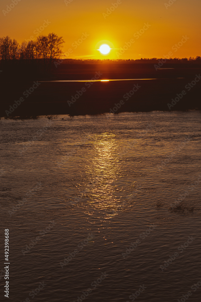 yellow orange sunset light over calm river Lielupe, Latvia