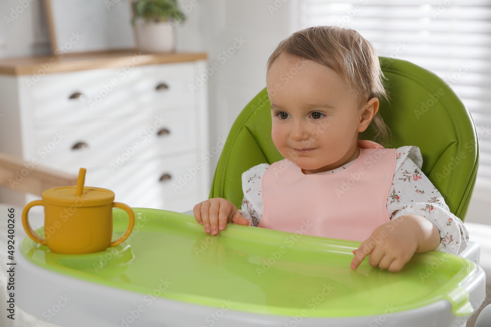 Cute little baby wearing bib in highchair at home Cute little baby wearing bib in highchair at home
