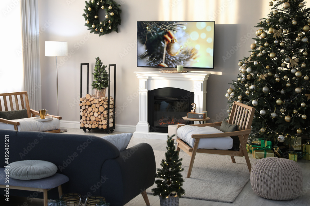 Modern TV set on light wall in room decorated for Christmas Modern TV set on light wall in room decorated for Christmas