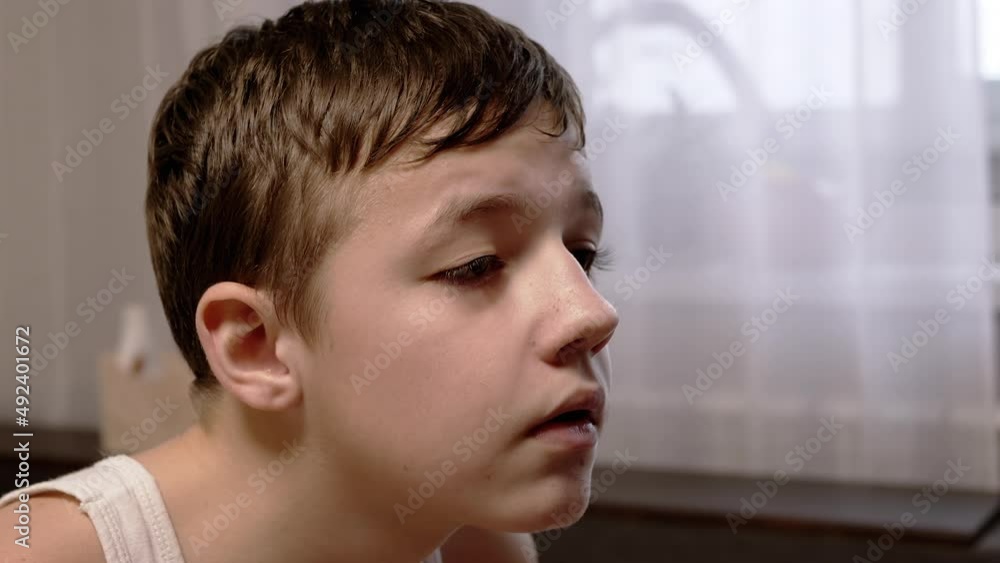 A Face of a Serious Child, Carefully Looking at the Monitor Screen. Side View. Profile of a focused teenager sitting in a room and studying, reading information from the TV screen. Home atmosphere. A Face of a Serious Child, Carefully Looking at the Monitor Screen. Side View. Profile of a focused teenager sitting in a room and studying, reading information from the TV screen. Home atmosphere.