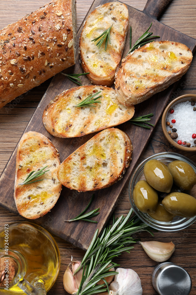 Tasty bruschettas with oil and rosemary on wooden table, flat lay Tasty bruschettas with oil and rosemary on wooden table, flat lay
