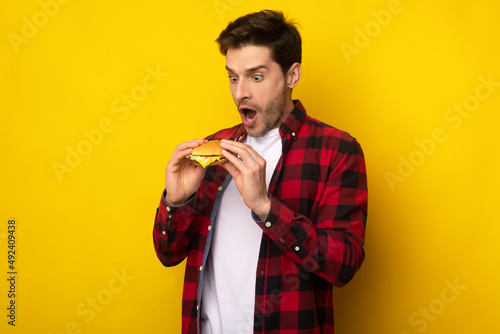 Funny Young Guy Holding Burger At Studio