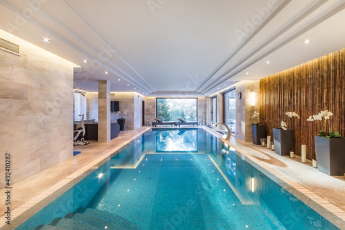 Magnificent indoor private pool with waterfall jet. Exercise equipment and sun beds. photo