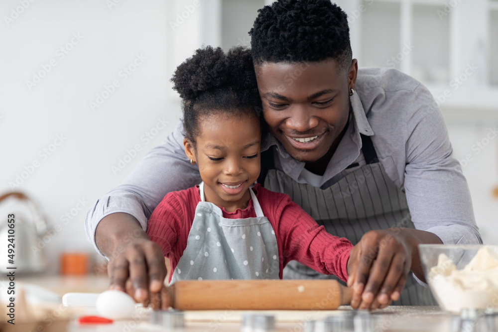 Black father and daughter rolling pastry dough and smiling Black father and daughter rolling pastry dough and smiling