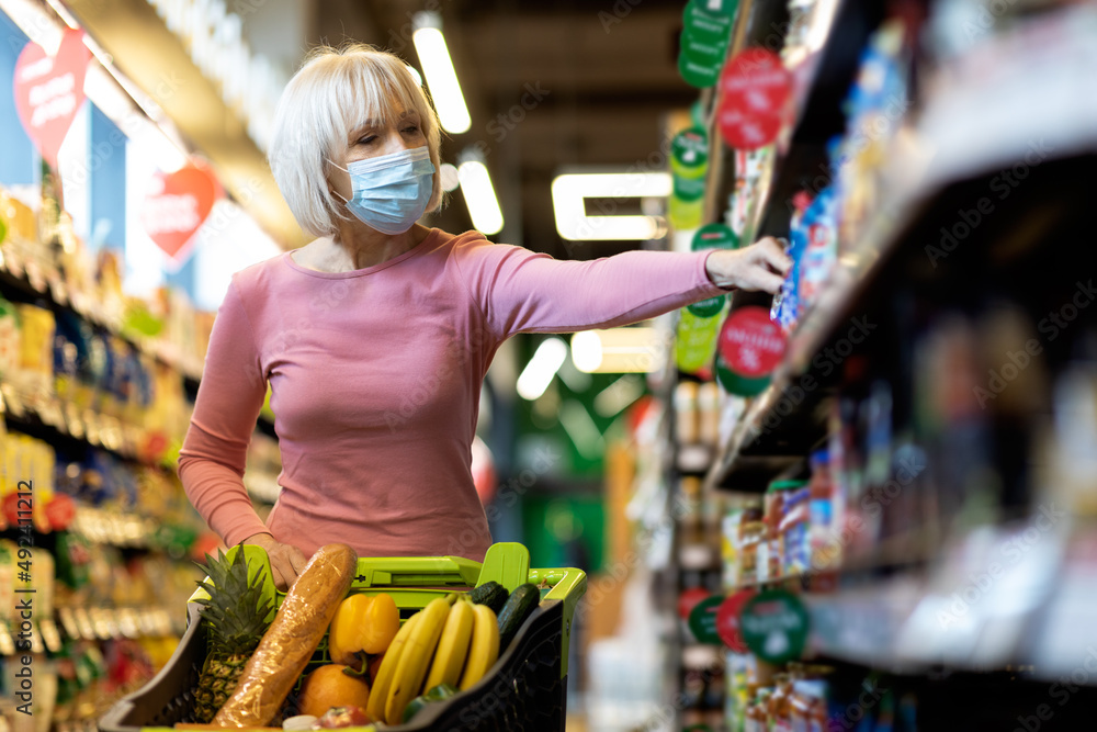 Granny in face mask shopping at supermarket while epidemic