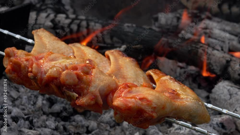 Close-up of raw chicken wings on the skewers placed above the open fire Close-up of raw chicken wings on the skewers placed above the open fire