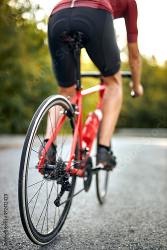 close-up wheels, cropped young man with athletic body shape riding bicycle with beautiful nature around. Concept of self discipline and motivation, healthy lifestyle. view from back.