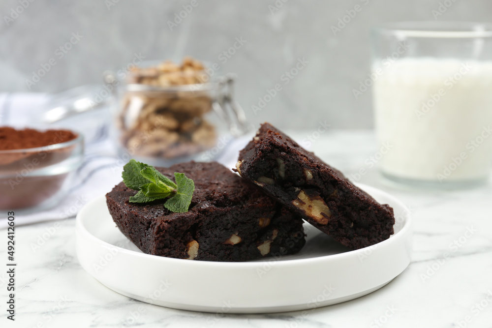 Delicious brownies with nuts and mint on white marble table