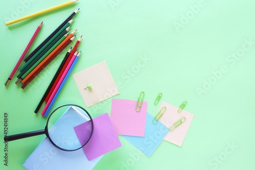 Stationery and an alarm clock, pastel colored paper, on a green background, top view, the concept of learning, education, back to school, holidays