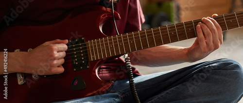 Cropped of man playing chords on electric guitar
