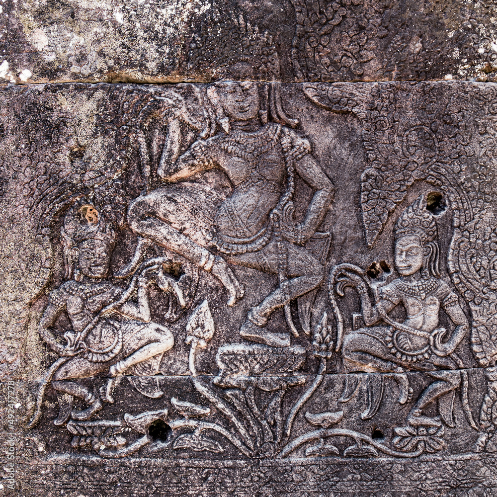 Fototapeta premium Stone-carved bas-relief with dancing apsaras in ancient Khmer temple in Angkor, Siem Reap, Cambodia